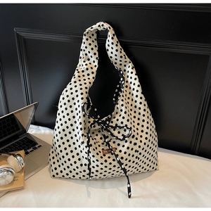 Detailed view of polka dot canvas tote bag with decorative bow and brand label