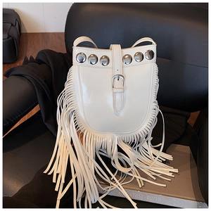 Detail of white bucket bag featuring silver rivets and long bohemian tassels