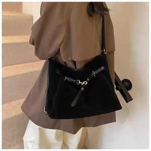 Close-up of black suede hobo bag with cross strap buckle and gold metal hardware