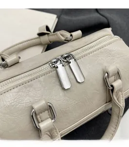 Vue détaillée des fermetures éclair doubles en métal sur le sac Boston en cuir beige