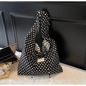Detailed view of polka dot canvas tote with bow tie closure and daily commute accessories