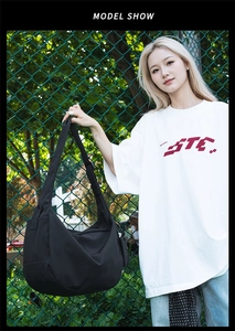 Close-up of black nylon hobo bag with wide adjustable strap on a female model outdoors