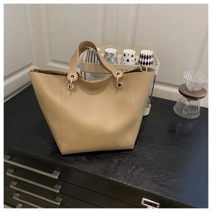 Detail of beige tote bag with golden metal rings on a wooden surface in a home setting
