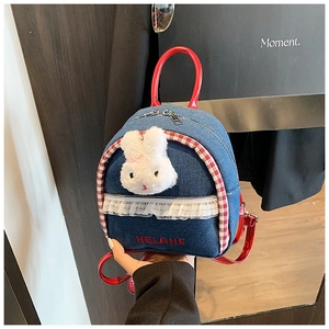 Detail of denim backpack featuring red patent leather straps and cute bunny charm