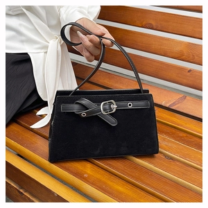 Détail du sac à bandoulière en daim noir mat avec boucle argentée sur un banc