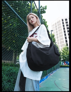 Detail of a black nylon dumpling bag with adjustable strap and small detachable pouch