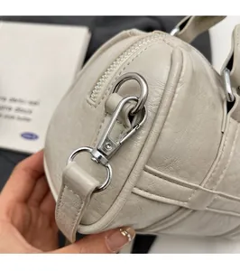 Détail de la boucle argentée et des coutures fines sur le sac oreiller en cuir beige