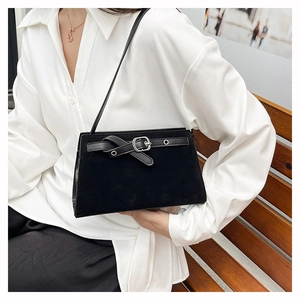 Vue détaillée du sac bandoulière en cuir mat noir avec boucle argentée sur un banc