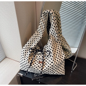 Close-up of polka dot canvas tote bag with black bow and brown label on a side table