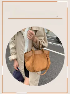 Close-up of a large brown suede tote bag with leather trim worn on a city street