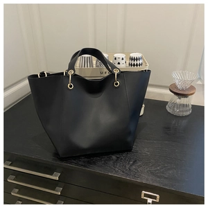 Top view of large black tote bag with gold eyelets on a dark wooden surface