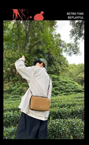 Close-up of tan tactical crossbody bag with Tactileyou logo in a lush green outdoor setting