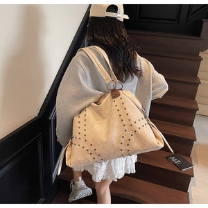 Detail of beige tote bag with metallic rivet studs and premium leather shoulder strap