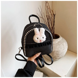 Detail of dark denim mini backpack with plush rabbit charm and lace trim accents