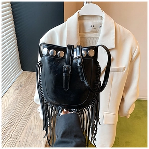 Detail of black faux leather bucket bag featuring silver metal studs and long fringe trim