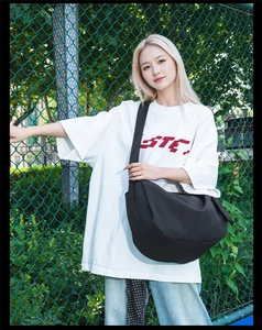 Outdoor shot of a black nylon crescent bag worn crossbody with adjustable wide strap