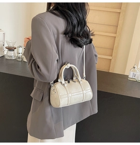 Sac polochon en PU brillant blanc cassé avec surpiqûres porté par un mannequin en ville