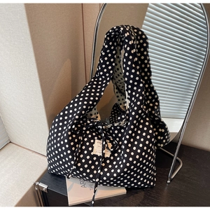 Detail of a black polka dot tote bag featuring a white fabric label and side tie closure