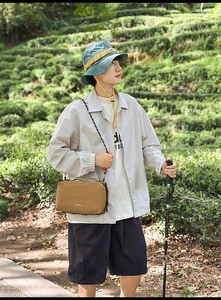 Outdoor leisure brown nylon crossbody bag worn by a model in a scenic tea garden setting