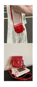 Detail of red leather mini saddle bag with adjustable strap and strawberry charm