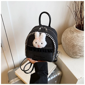 Detail of dark denim mini backpack with plush rabbit ornament and checkered trim