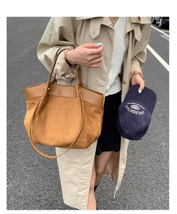 Detail of a brown suede and leather tote bag styled with a casual trench coat