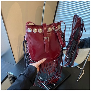 Detail of burgundy leather bucket bag with silver studs and long fringe accents