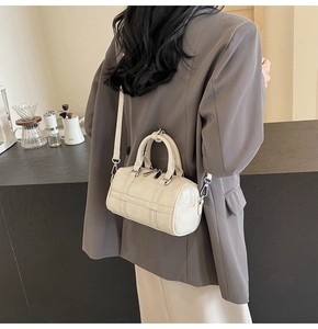 Gros plan d'un sac Boston blanc crème avec coutures croisées et détails métalliques argentés