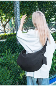 Detail of a large black nylon crescent bag showing the detachable side pouch and strap hook