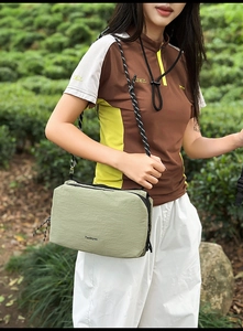 Detail of light green nylon crossbody bag with woven rope strap and branded logo detail