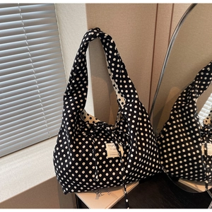Close-up of black canvas tote bag with white polka dots and decorative fabric label