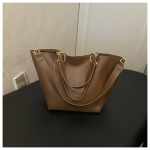 Detail of a brown tote bag featuring golden metal rings and durable double straps