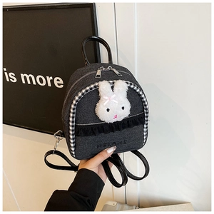 Detail of mini denim backpack with plush bunny and black lace trim, held by hand