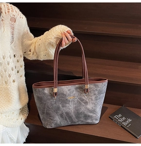 Close-up of grey marble texture tote bag with golden metal logo and brown handles