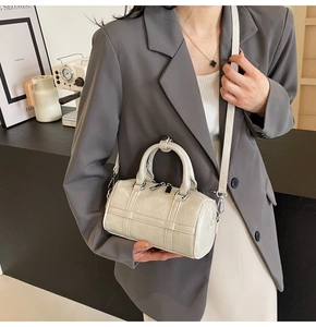 Détail d'un sac cylindrique blanc en cuir plissé brillant avec fermeture éclair argentée