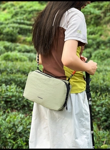 Green nylon crossbody bag shown in outdoor hiking setting with adjustable black strap