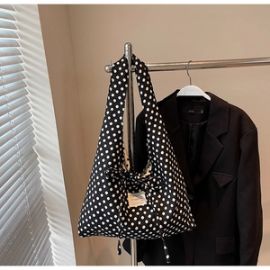 Detail of a large polka dot canvas tote bag featuring a square fabric label on wide straps