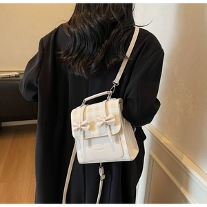 Dettaglio zaino bianco crema con patta a quadri beige e fiocchi decorativi 3D