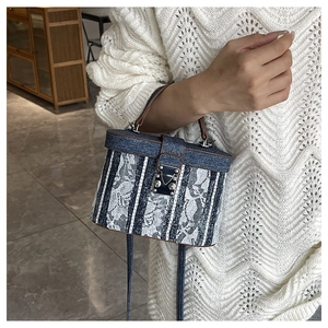 Detail of denim and white lace bucket bag featuring a vintage metal clasp and top handle