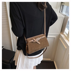 Détail d'un sac à bandoulière vintage en daim marron porté par une personne de dos