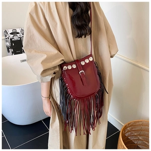 Detail showing deep red patent leather saddle bag with long tassels and silver studs