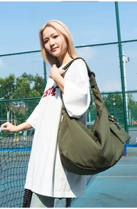 Close-up of olive green nylon dumpling bag with adjustable wide strap in outdoor setting