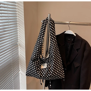 Detail of a large polka dot tote bag with a decorative bow and white woven label