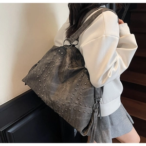 Detail of grey tote bag with silver studs and wide shoulder strap on a model