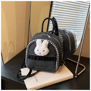 Detail of denim mini backpack with plush bunny head and ruffle trim on black table