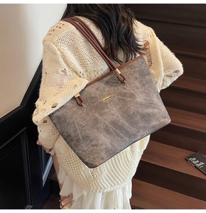 Chic grey suede tote bag with brown straps worn by a model on wooden stairs