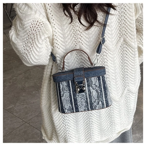 Detail of denim and white lace bucket bag with vintage metal clasp and top handle