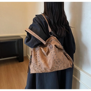 Detail of vintage brown studded hobo shoulder bag with matte leather texture and metal rings