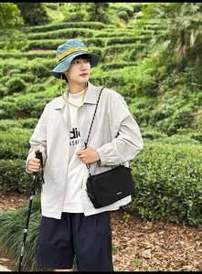 Detail of black nylon crossbody bag with adjustable patterned strap in a hiking setting
