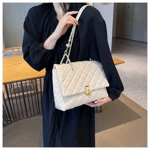 Detail of quilted beige flap bag featuring a golden twist lock and metal chain strap